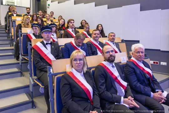 Grupa osób w eleganckich strojach z odznaczeniami na ceremonii.