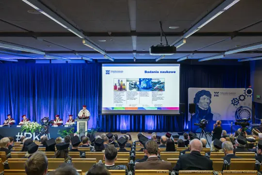 Konferencja naukowa z prezentacją badań i uczestnikami w auli.