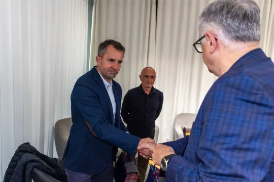 Mężczyźni w garniturach podają sobie ręce w biurze.
