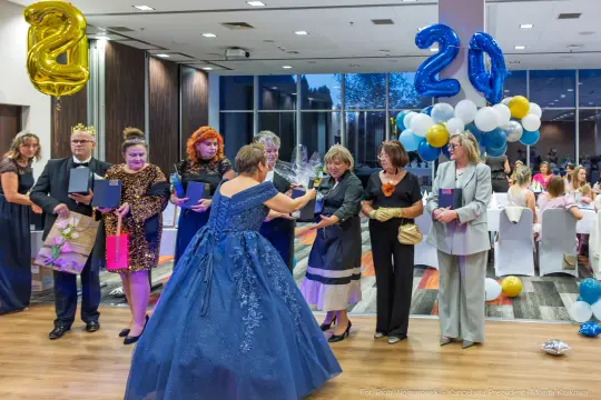 Uroczystość z okazji 20-lecia, goście w eleganckich strojach, dekoracje balonowe.