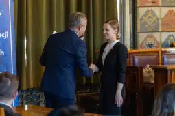 Uścisk dłoni podczas wręczenia nagrody w formalnym otoczeniu.
