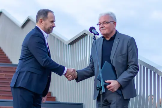 Dwaj mężczyźni podają sobie ręce podczas uroczystości.