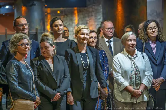 Grupa osób w eleganckich strojach na wydarzeniu kulturalnym.