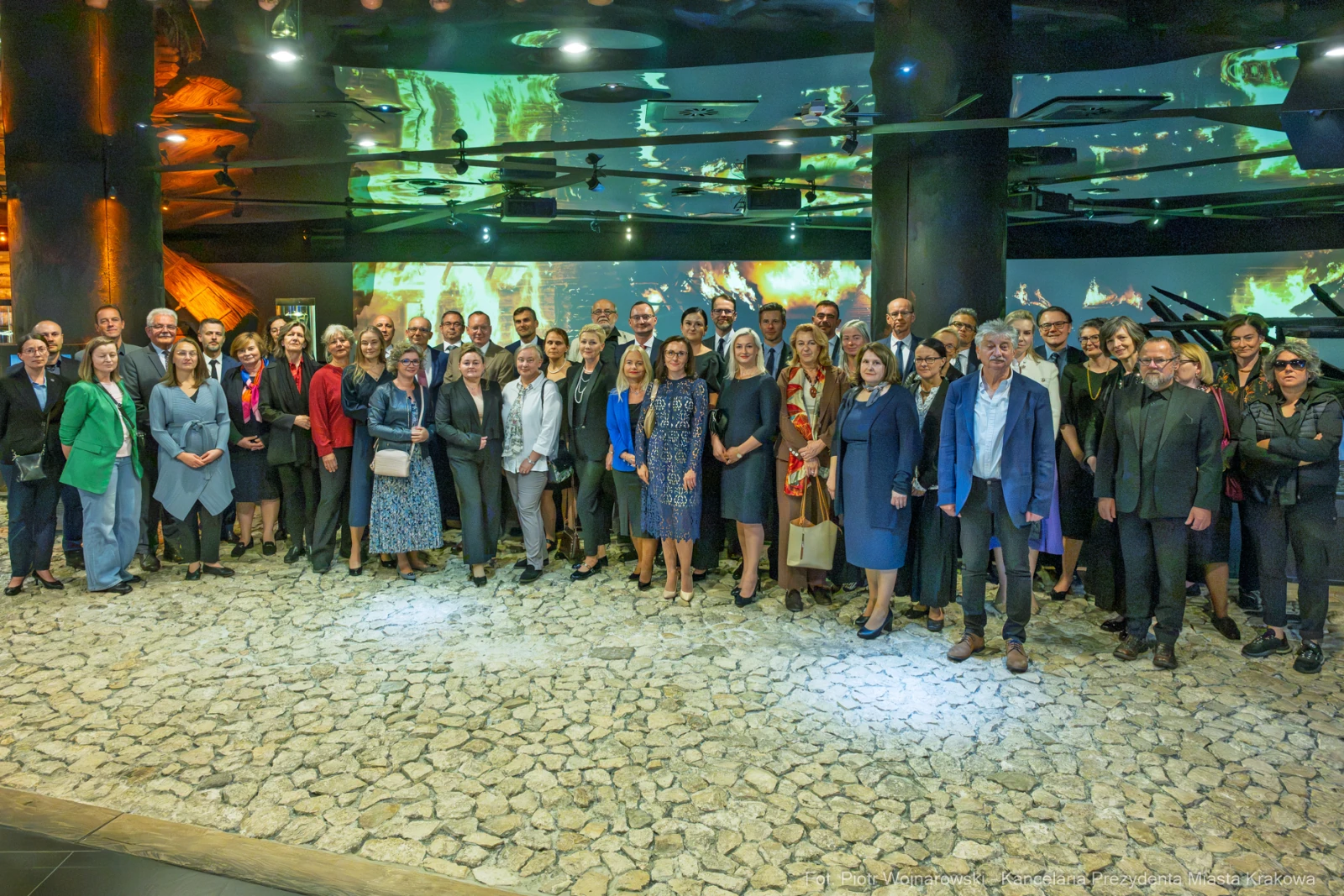 Grupa ludzi w eleganckich strojach na wydarzeniu w nowoczesnym wnętrzu.  Autor: Piotr Wojnarowski
