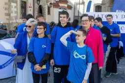 Grupa osób w niebieskich koszulkach, uśmiechających się i pozujących do zdjęcia.