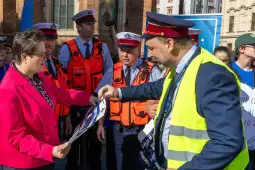 Spotkanie urzędników w kamizelkach odblaskowych z dokumentami w rękach.