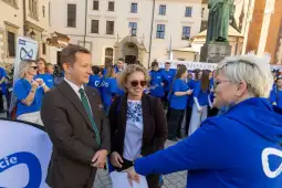 Spotkanie ludzi w niebieskich koszulkach, rozmowy i aktywności na placu.