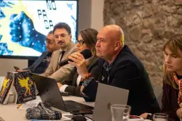 Panel dyskusyjny z pięcioma osobami, jedna z nich mówi do mikrofonu, w tle grafika z hasłem.