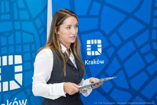 Kobieta w eleganckim stroju prezentuje materiały w Krakowie.