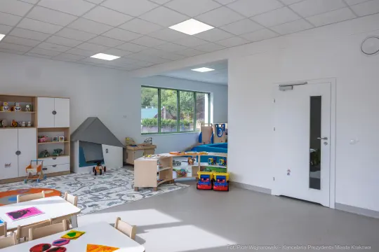 Nowoczesna sala przedszkolna z kolorowymi zabawkami i kącikiem do zabawy.