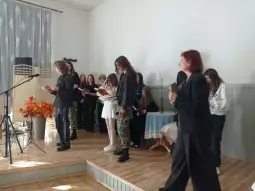 Grupa osób w strojach formalnych i codziennych, uczestniczących w wydarzeniu kulturalnym.
