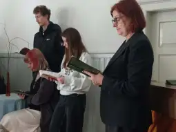 Grupa osób trzymających książki, uczestniczących w wydarzeniu w jasnym wnętrzu.