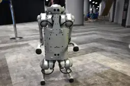 Robot humanoidalny z metalową konstrukcją, stojący na dwóch nogach.
