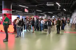 Tłum ludzi w hali wystawowej, stoiska informacyjne i interakcje uczestników.