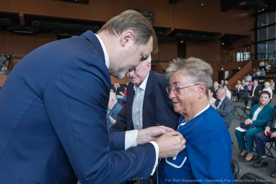 Uroczystość wręczenia odznaczeń, starsza kobieta odbiera medal.