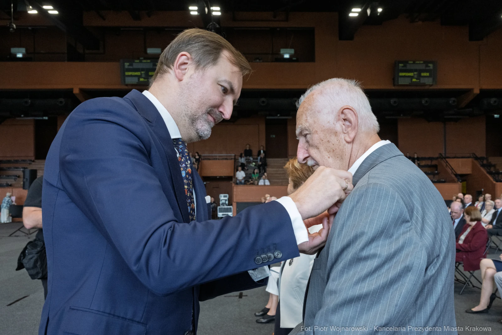 Mężczyzna przypina odznaczenie drugiemu mężczyźnie podczas uroczystości.  Autor: Piotr Wojnarowski