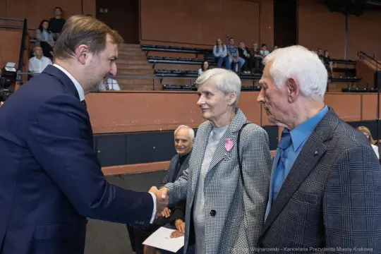 Spotkanie trzech osób, w tym dwóch starszych ludzi, podczas ceremonii wręczenia odznaczeń.