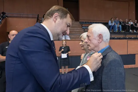 Wręczenie odznaczenia mężczyźnie przez oficjela w obecności innych osób.