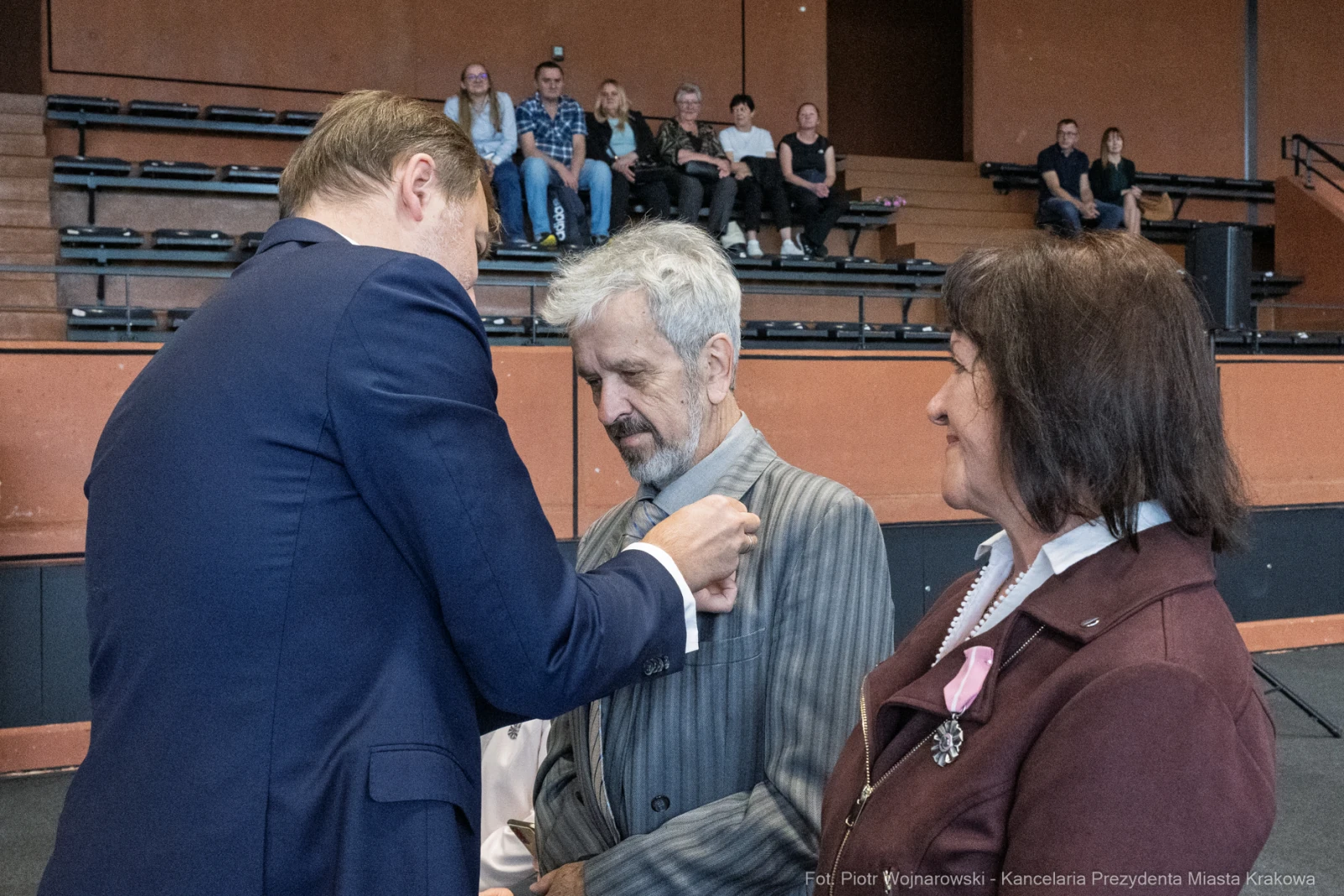 Ceremonia wręczenia odznaczeń w sali, dwie osoby w eleganckich strojach, mężczyzna odbierający medal.  Autor: Piotr Wojnarowski