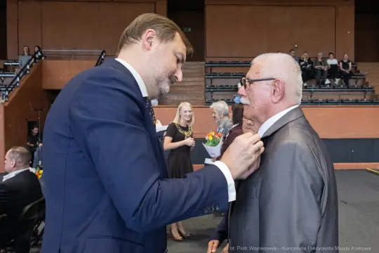 Mężczyzna poprawia krawat innemu mężczyźnie w eleganckim otoczeniu.