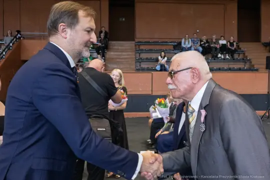 Uścisk dłoni dwóch mężczyzn podczas ceremonii wręczenia nagród.