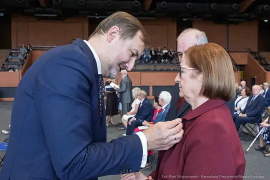 Wręczenie odznaczenia przez mężczyznę kobiecie podczas uroczystości.