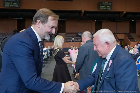 Dwaj mężczyźni uścisnęli sobie dłonie podczas wydarzenia w sali konferencyjnej.