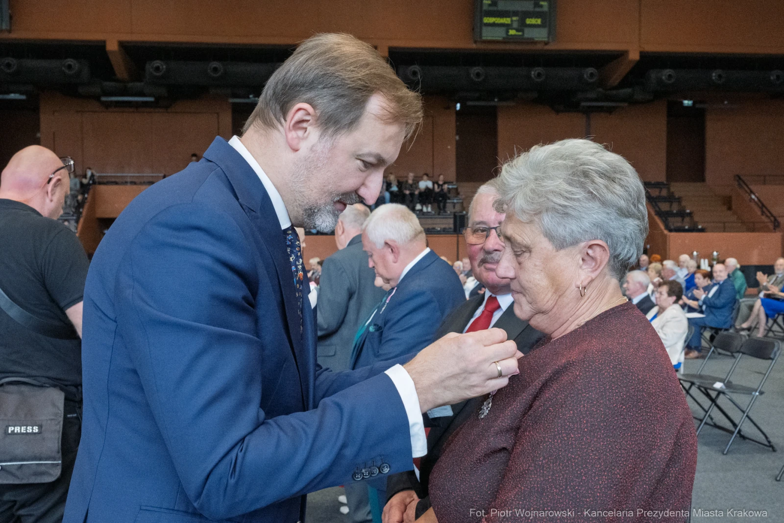 Wręczenie odznaczenia przez mężczyznę starszej kobiecie podczas uroczystości.  Autor: Piotr Wojnarowski
