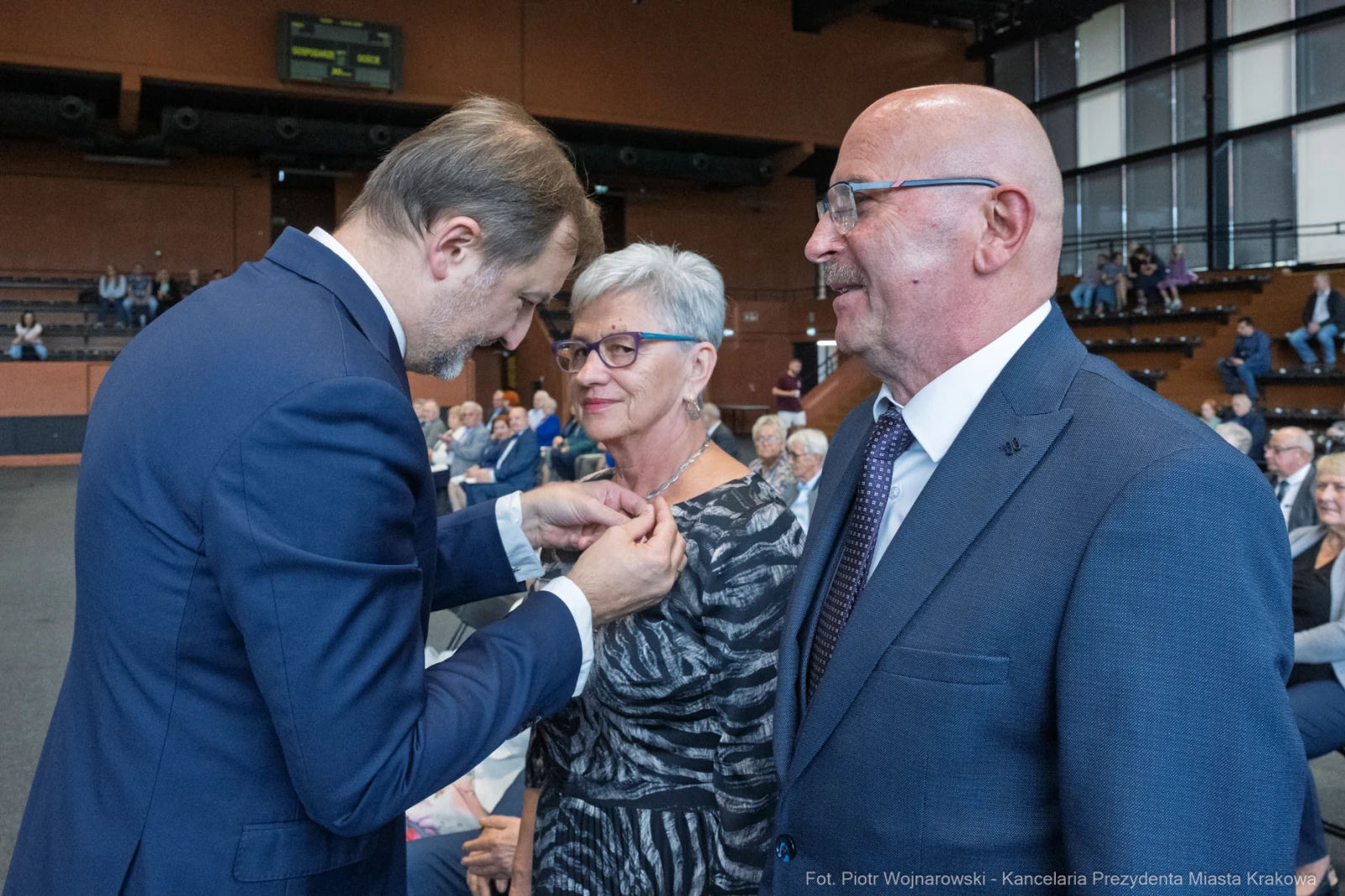Wręczenie odznaczenia przez mężczyznę kobiecie w towarzystwie drugiego mężczyzny.  Autor: Piotr Wojnarowski