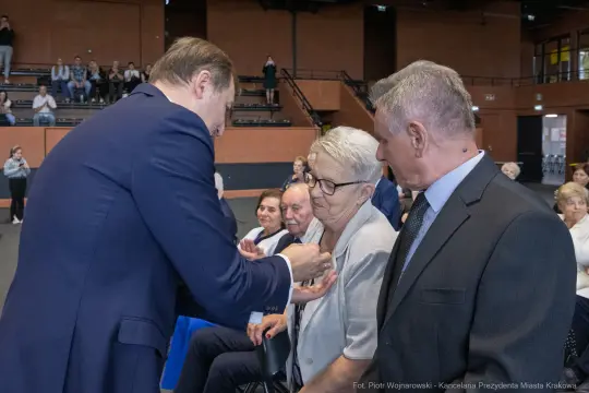 Wręczenie odznaczeń osobom starszym podczas uroczystości w sali.