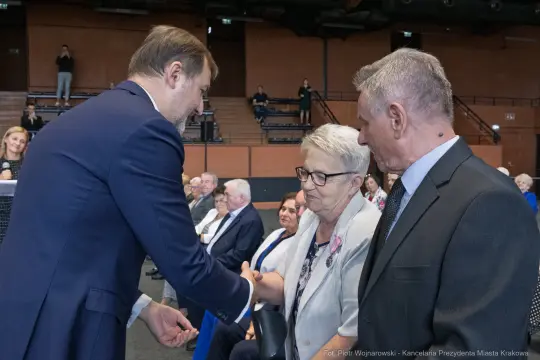 Uroczystość wręczenia nagród, uściski dłoni i uśmiechy uczestników.