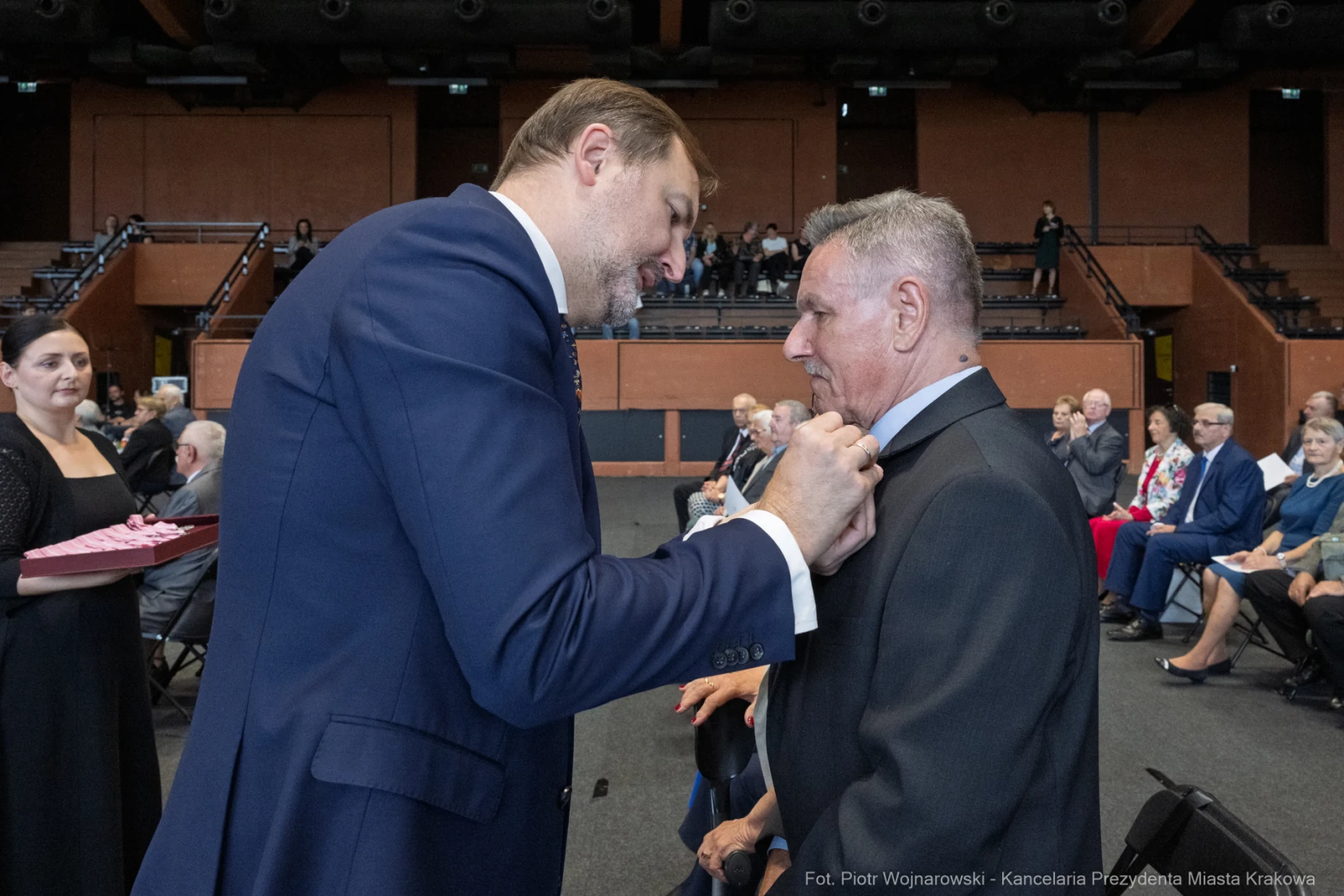 Mężczyzna przypina odznaczenie drugiemu mężczyźnie podczas ceremonii wręczenia nagród.  Autor: Piotr Wojnarowski