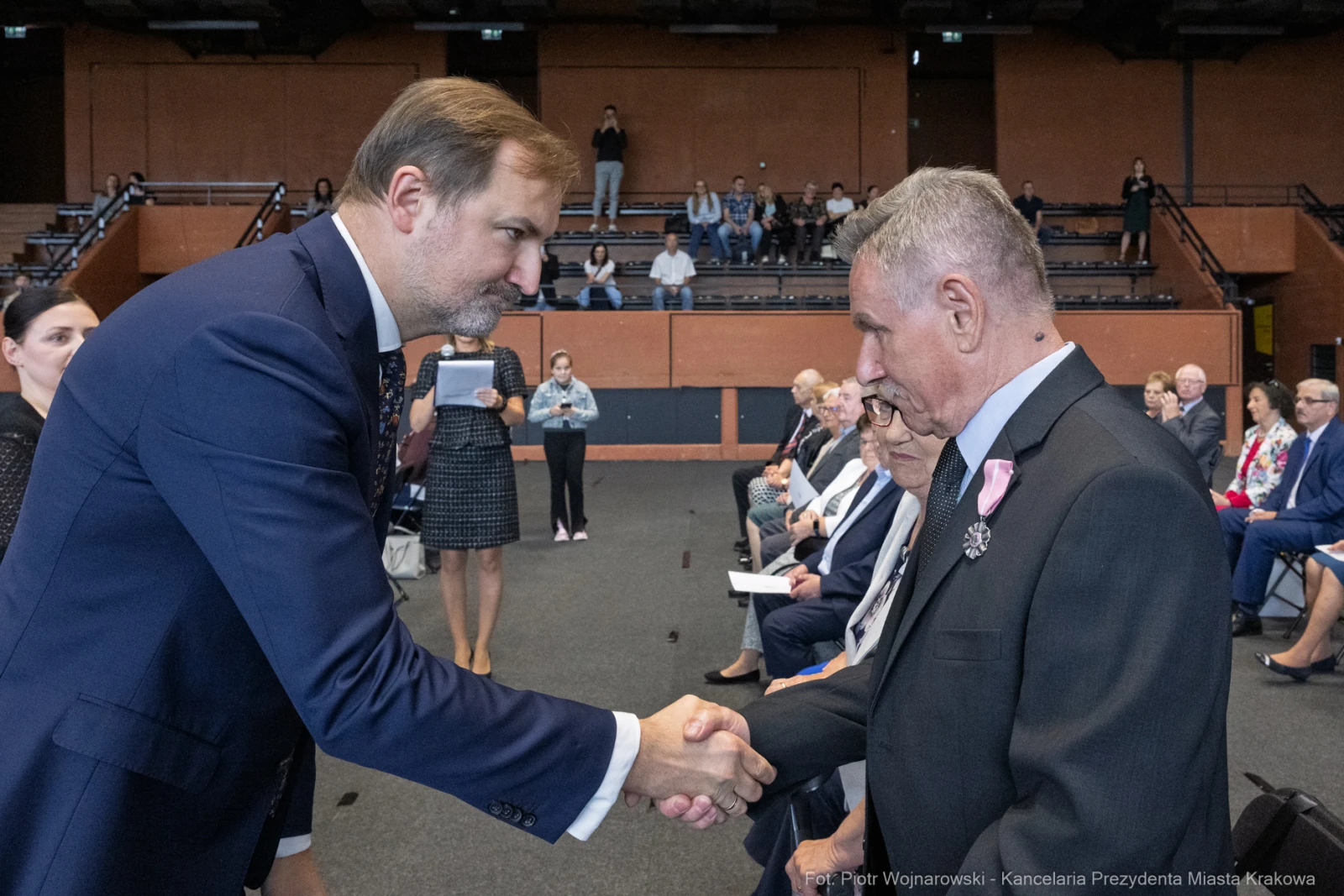 Mężczyźni podają sobie ręce podczas uroczystości w sali.  Autor: Piotr Wojnarowski