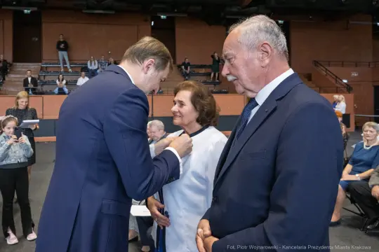 Wręczenie odznaczenia przez mężczyznę kobiecie w obecności innych osób.