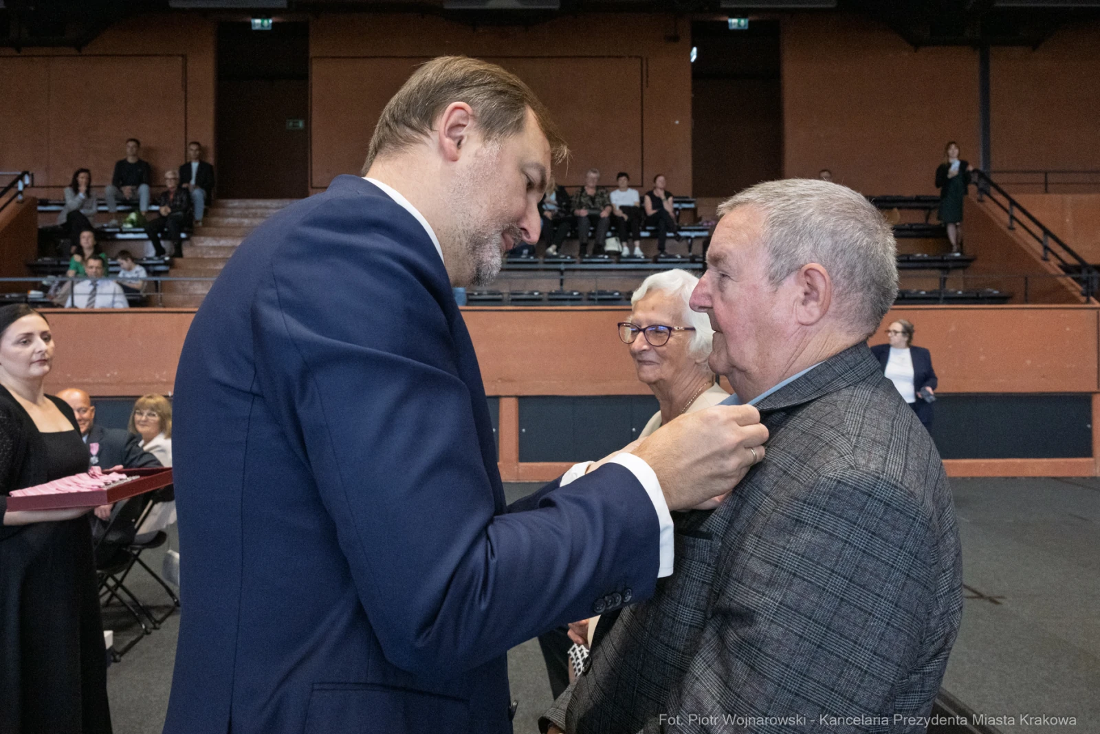Wręczenie odznaczenia mężczyźnie w eleganckim garniturze podczas uroczystości.  Autor: Piotr Wojnarowski