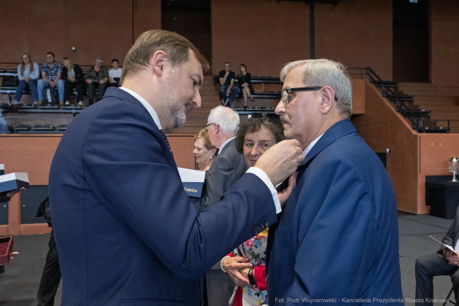 Mężczyzna przypina odznaczenie innemu mężczyźnie w towarzystwie kobiet.  Autor: Piotr Wojnarowski