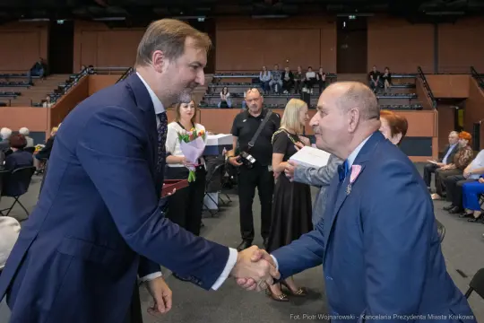 Uścisk dłoni dwóch mężczyzn podczas uroczystości wręczenia nagród.