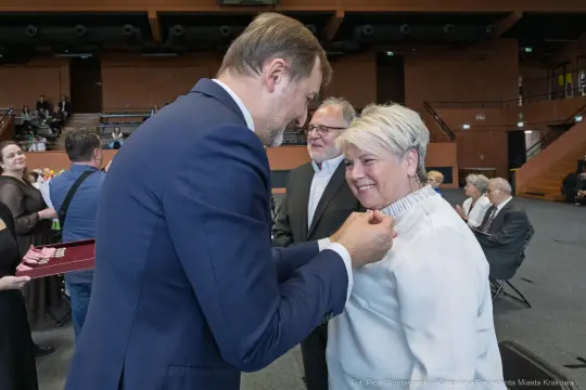 Wręczenie odznaczenia kobiecie podczas uroczystości w sali.
