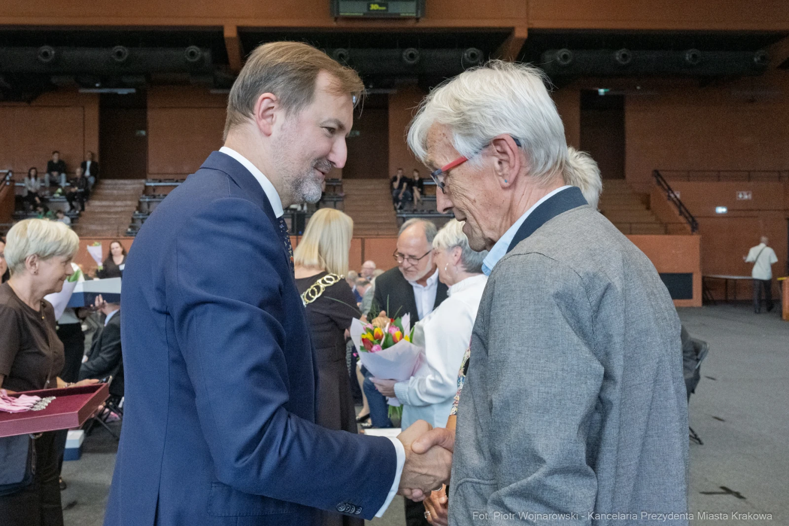 Uroczystość wręczenia nagród, mężczyźni w garniturach wymieniają uściski dłoni.  Autor: Piotr Wojnarowski