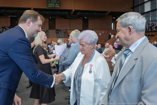 Wręczenie odznaczeń w trakcie uroczystości, uściski dłoni i gratulacje.