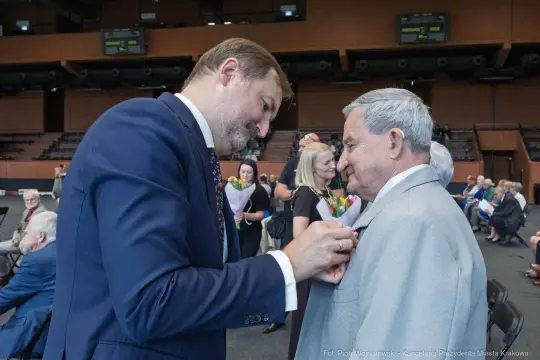 Mężczyzna przypina odznaczenie innemu mężczyźnie podczas uroczystości.