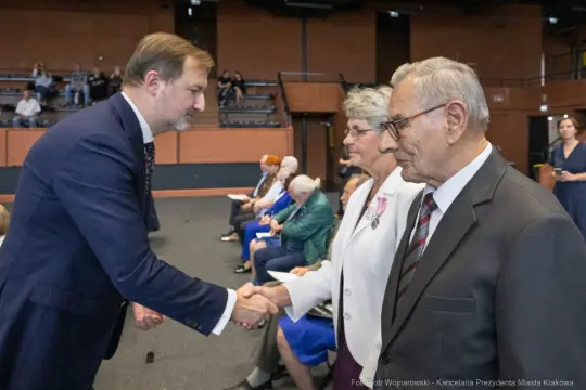 Uścisk dłoni między mężczyzną a starszymi osobami podczas uroczystości.