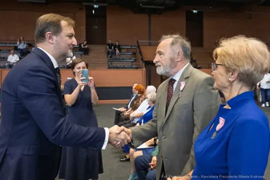 Uroczystość wręczenia odznaczeń, mężczyzna podaje rękę innemu mężczyźnie.