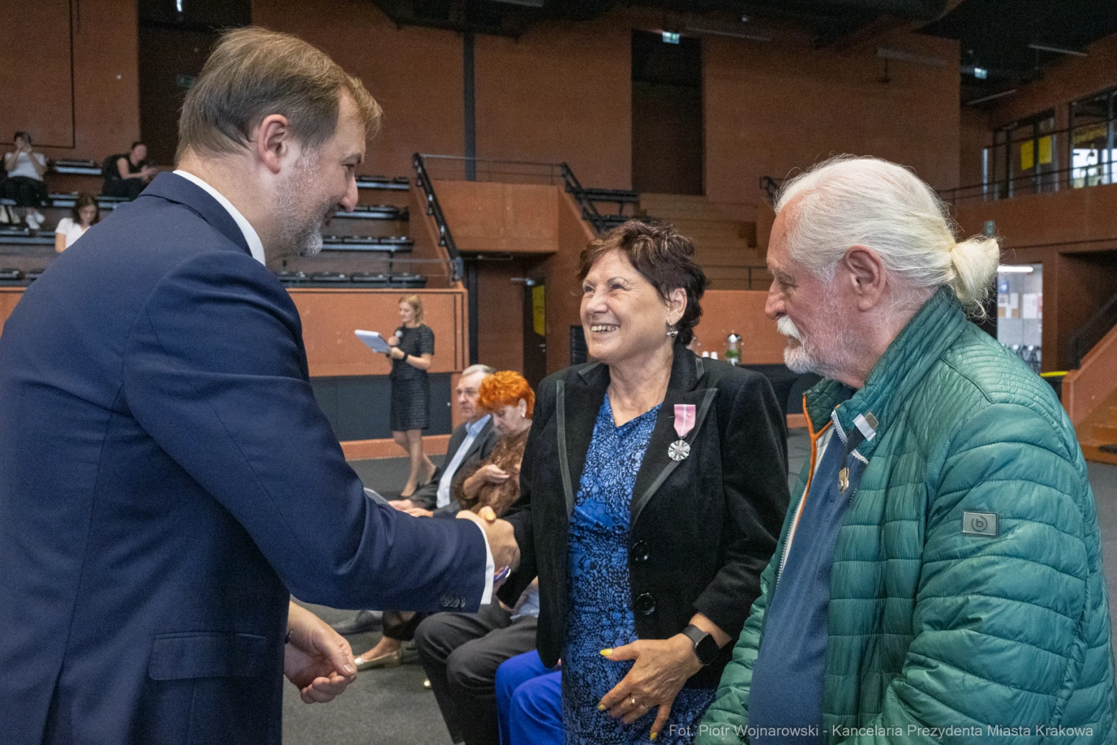 Uścisk dłoni między mężczyzną a kobietą, obok starszy mężczyzna z białymi włosami.  Autor: Piotr Wojnarowski