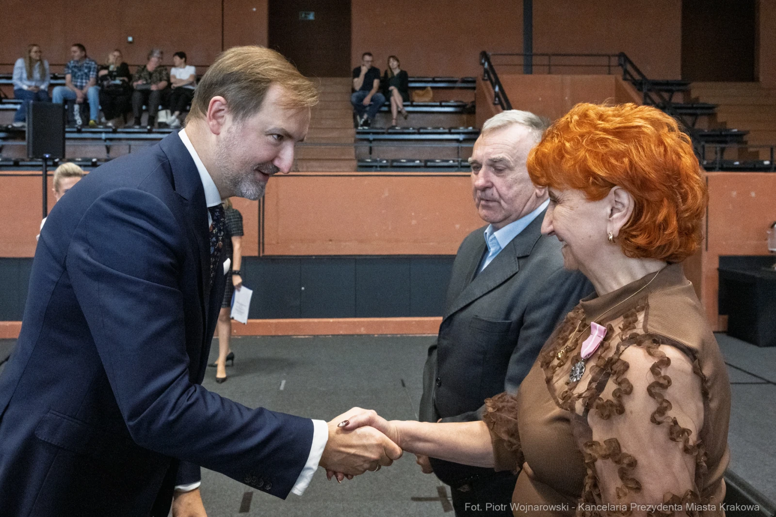 Mężczyzna w garniturze podaje rękę kobiecie z rudymi włosami, w tle inni uczestnicy wydarzenia.  Autor: Piotr Wojnarowski