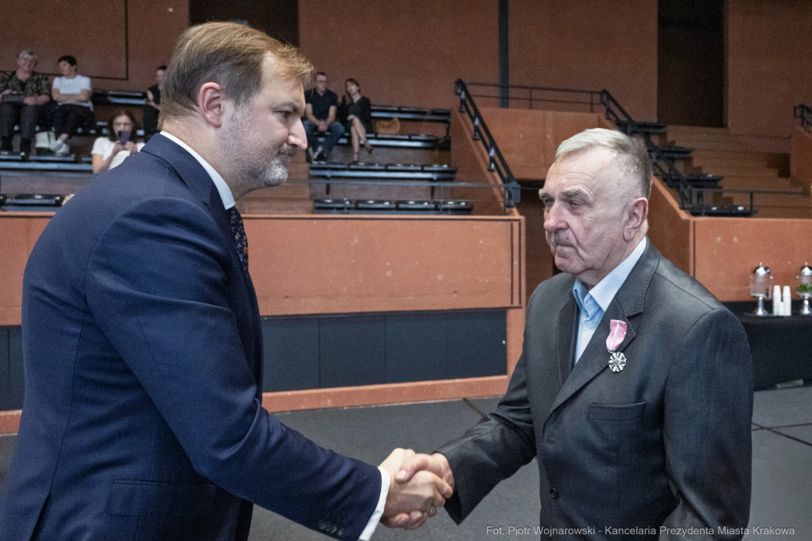 Wręczenie odznaczenia, mężczyźni uściski dłoni, ceremonia w sali.  Autor: Piotr Wojnarowski