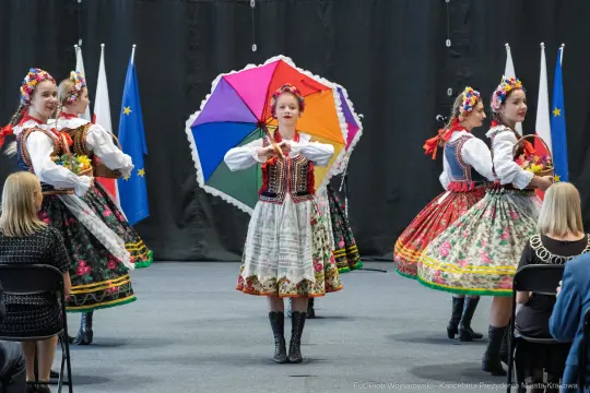 Tancerki w tradycyjnych strojach ludowych z parasolkami podczas występu.