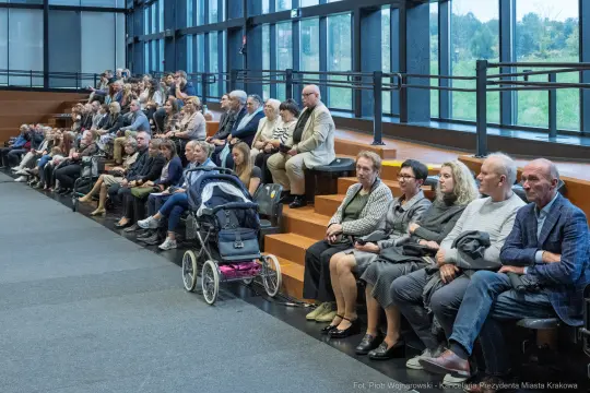 Grupa ludzi siedzących na schodach w nowoczesnym wnętrzu.