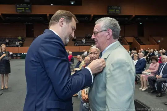 Wręczenie odznaczenia mężczyźnie podczas uroczystości w sali.