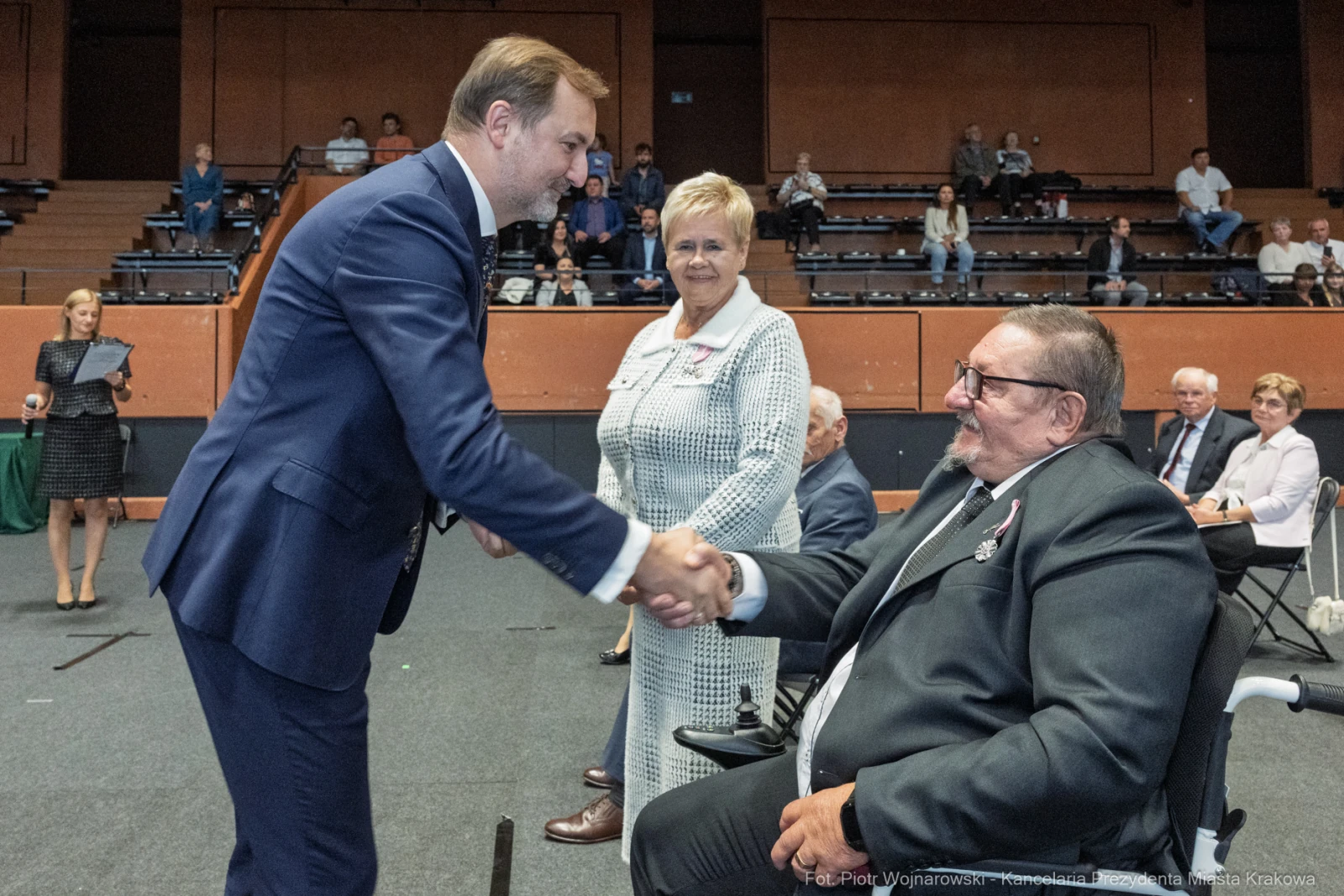 Uścisk dłoni między mężczyzną a starszym mężczyzną w wózku, obok stoi kobieta.  Autor: Piotr Wojnarowski